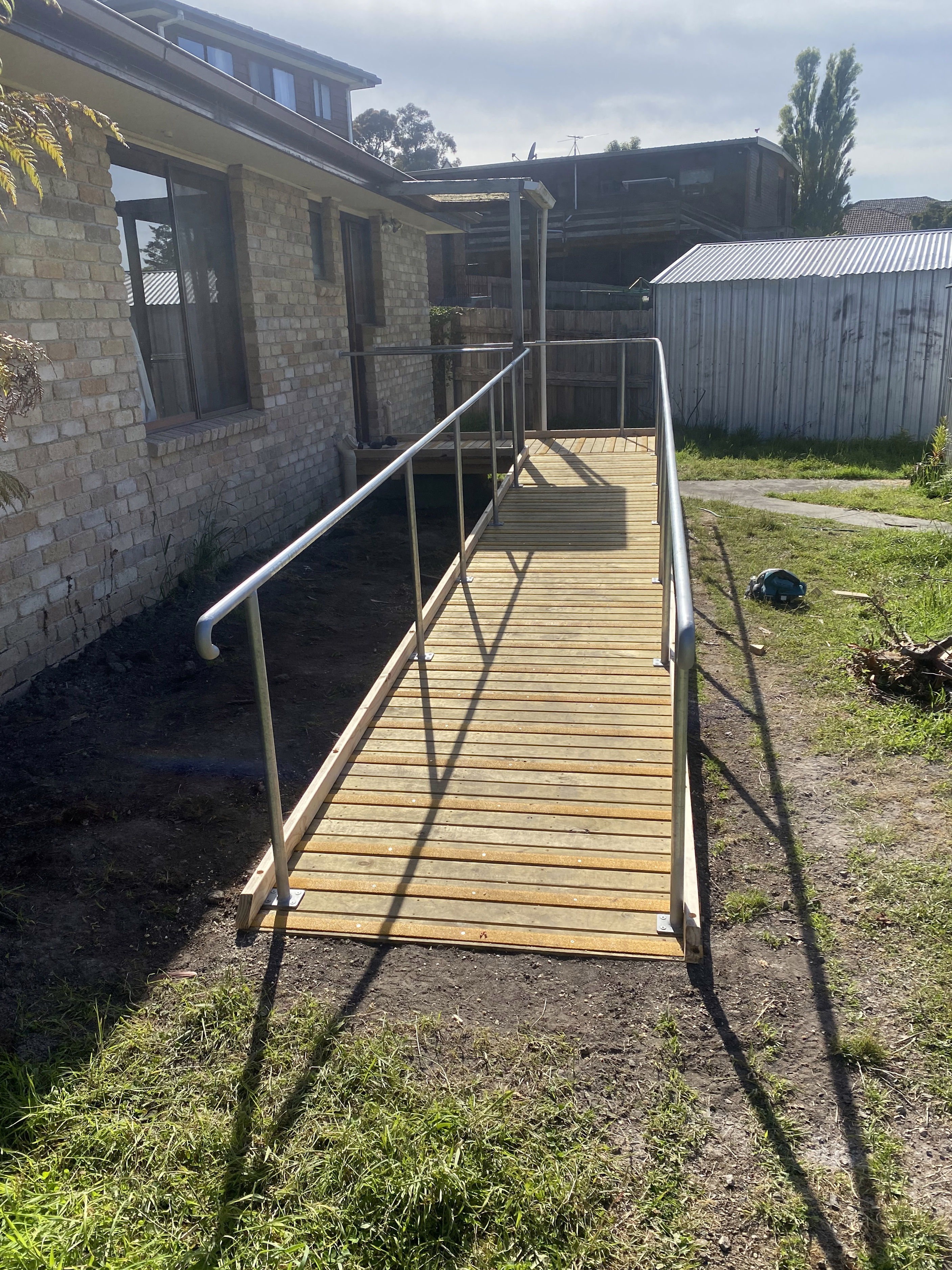 A wooden wheelchair ramp with railings outside a home